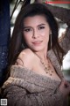 A beautiful young woman leaning against a blue pole.