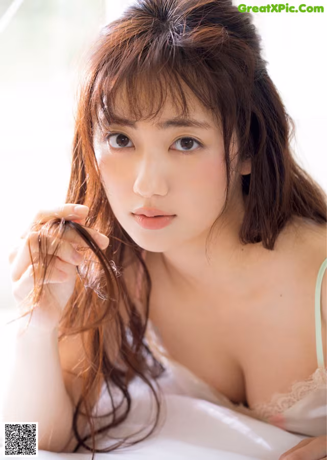A woman with long brown hair laying on a bed.