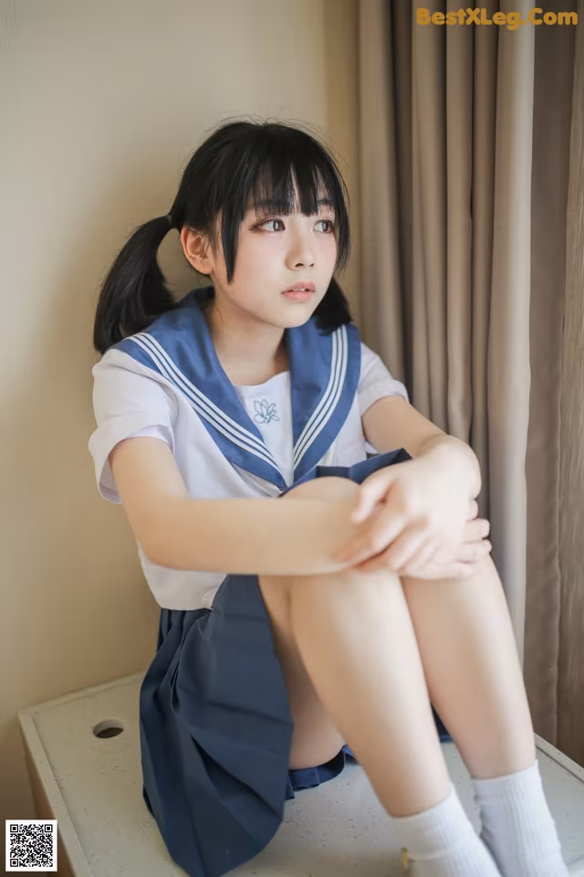 A woman in a school uniform sitting on a table.