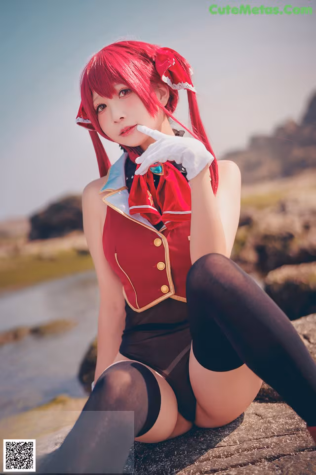 A woman in a red and black outfit sitting on a rock.