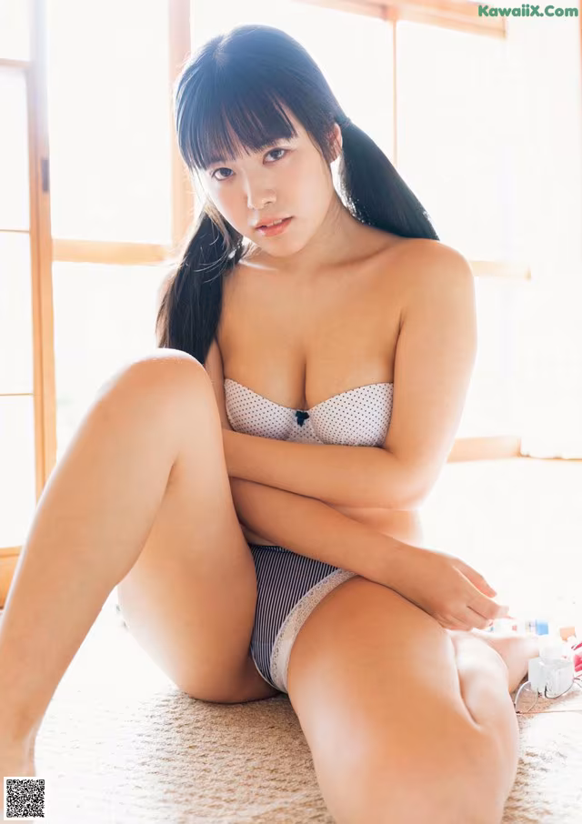 A woman in a white and black bikini sitting on the floor.