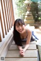 A young woman laying on a wooden bench smiling.