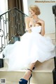 A woman in a white dress sitting on a set of stairs.