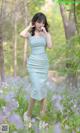 A woman in a blue dress standing in a field of flowers.