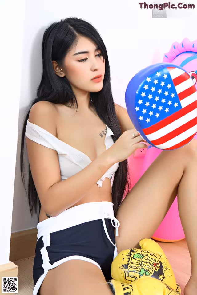 A woman sitting on the floor holding a ball with an American flag on it.