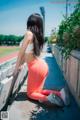 A woman in a white top and orange leggings sitting on a bench.