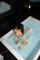 A naked woman is sitting in a bathtub with water.