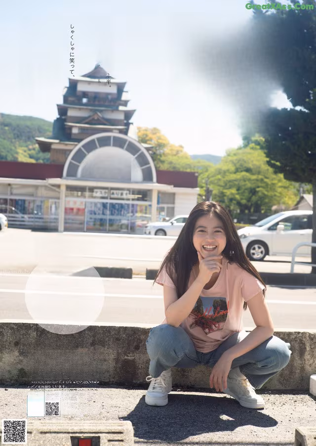 A woman sitting on the curb in front of a building.