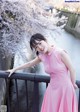 A woman in a pink dress standing on a bridge.