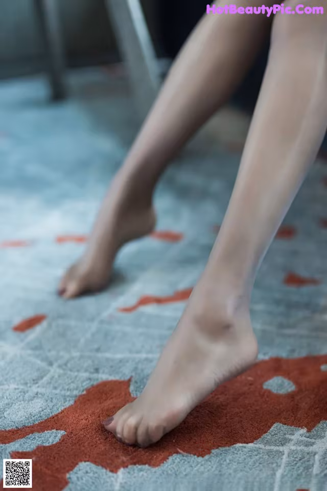 A woman's bare feet on a rug on the floor.