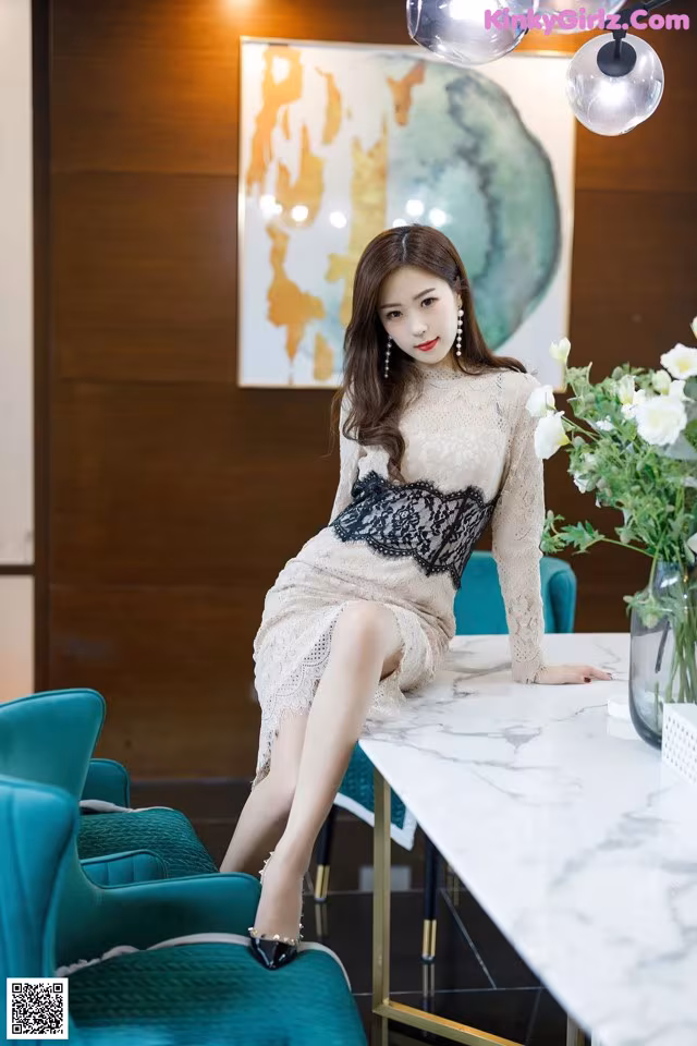 a woman sitting at a table with a vase of flowers
