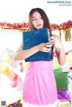 A woman in a pink dress holding a blue box.